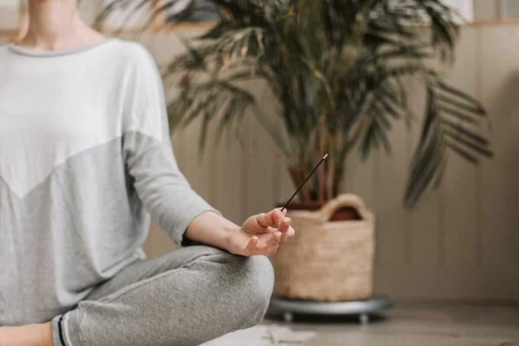 Pessoa Meditando sentada no chão da sala.