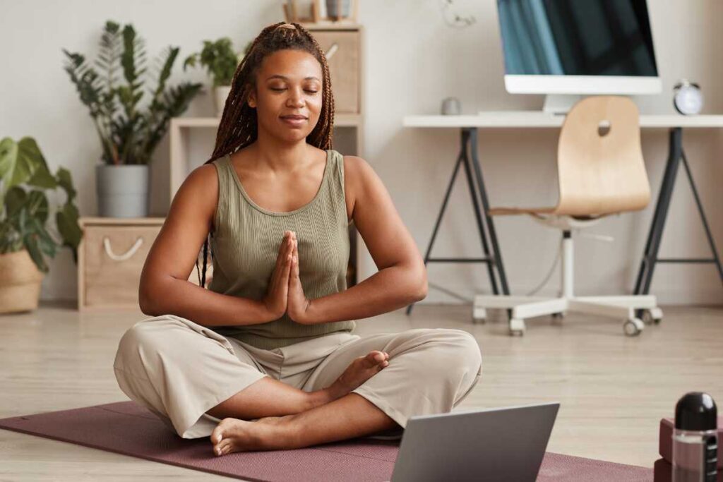 Mulher meditando sentada no chão de seu escritório.