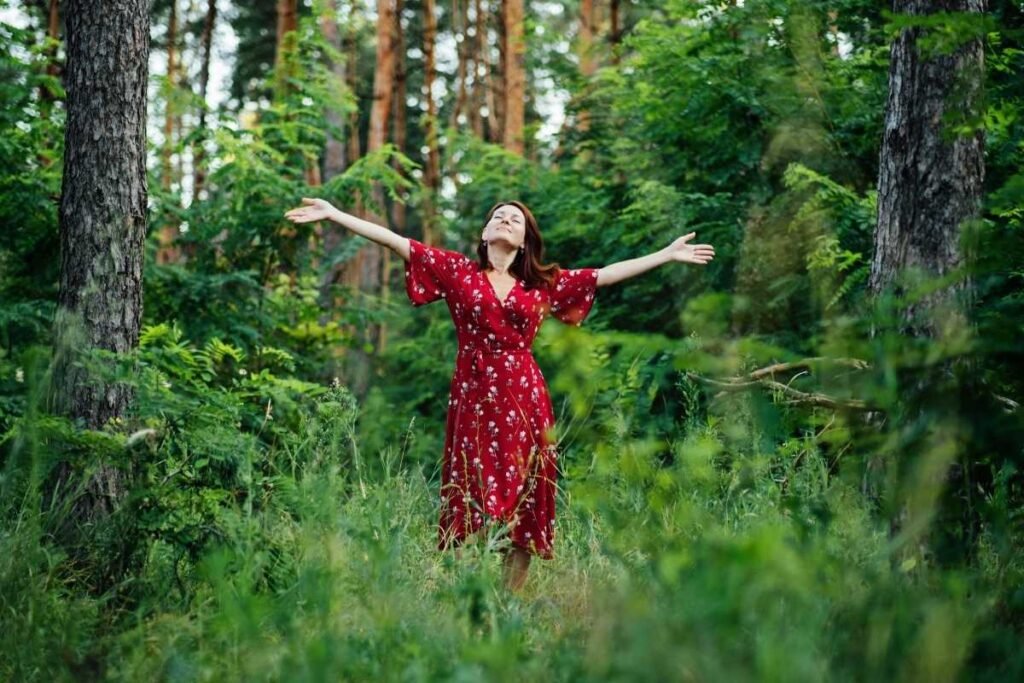 Mulher de braços abertos em contato com a natureza, aproveitando o tempo livre